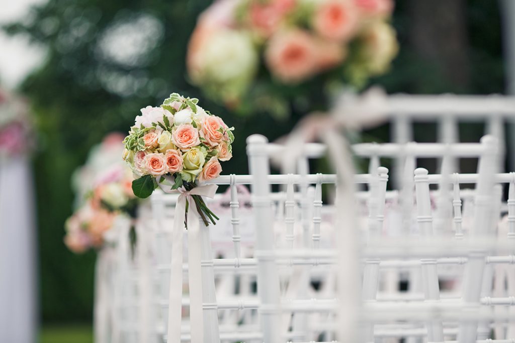 Little bouquets twined to the backs of white chairs